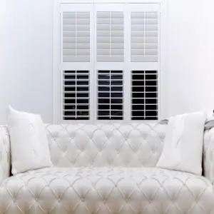 Elegant white custom wood California shutters framing wide bedroom windows for enhanced privacy